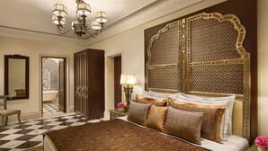 Une chambre à coucher luxueuse, dotée d’un grand lit, d’une tête de lit décorée et d’un lustre.