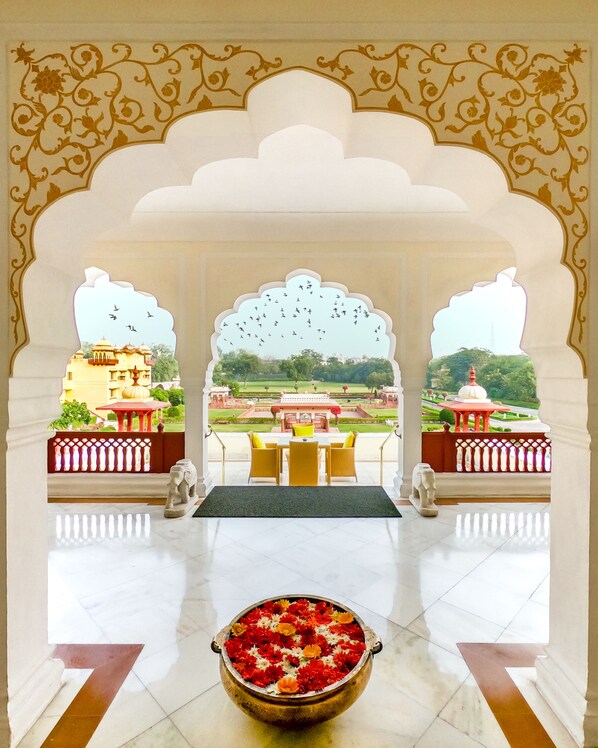 A traditional Indian palace with a courtyard view, a dining area with yellow chairs, and a decorative pot of flowers in the center. - Jai Mahal Palace (Jaipur)