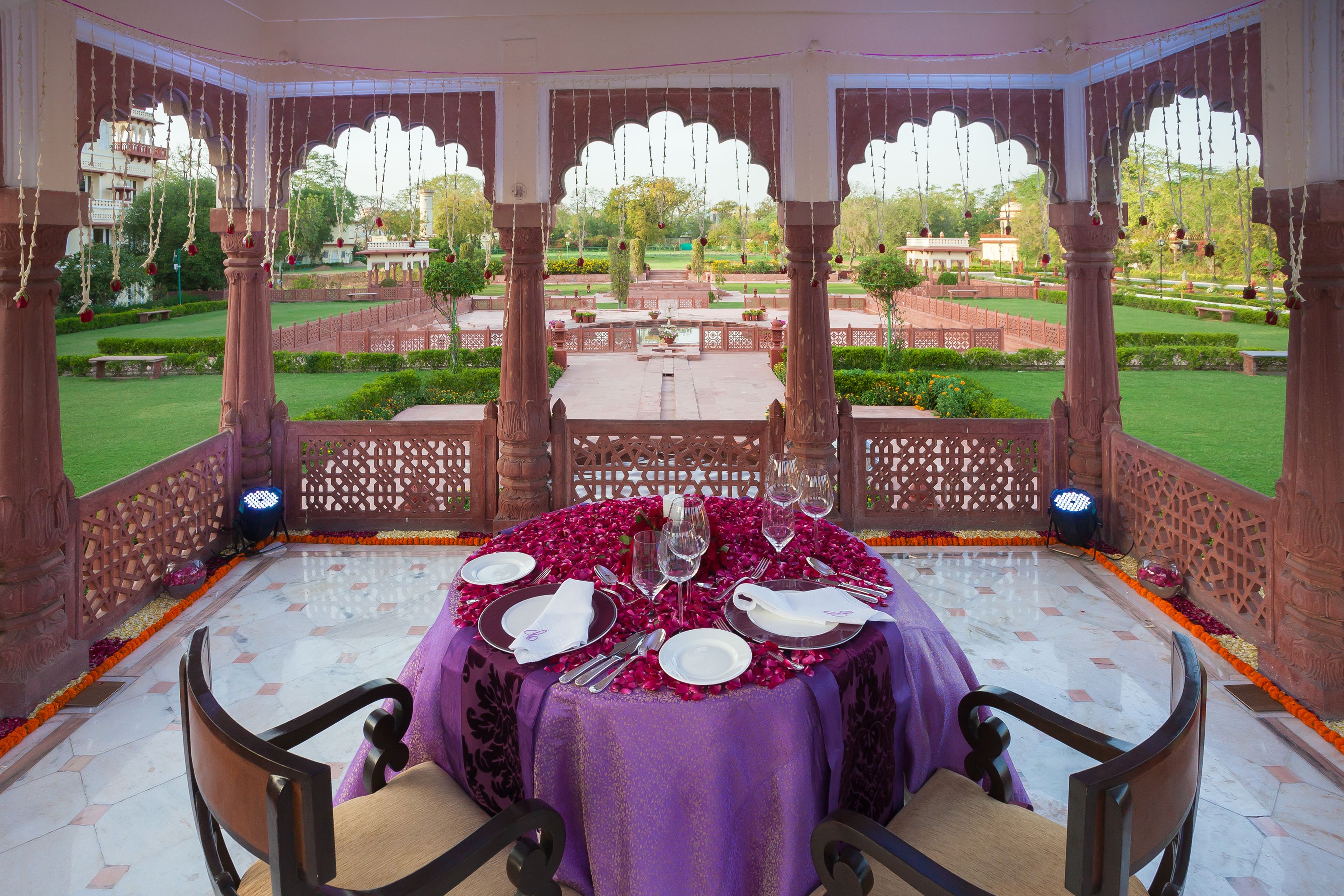 A dining area with a table set for four, surrounded by a garden view.