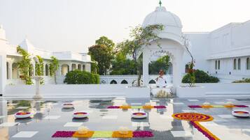 A courtyard with a reflective floor, white buildings, and a central white gazebo.