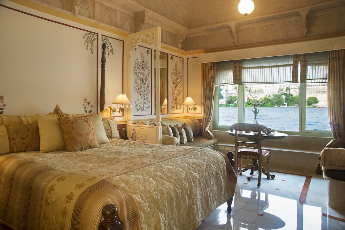 Ein luxuriöses Schlafzimmer mit einem großen Bett, einer Sitzecke am Fenster und Blick auf das Wasser.