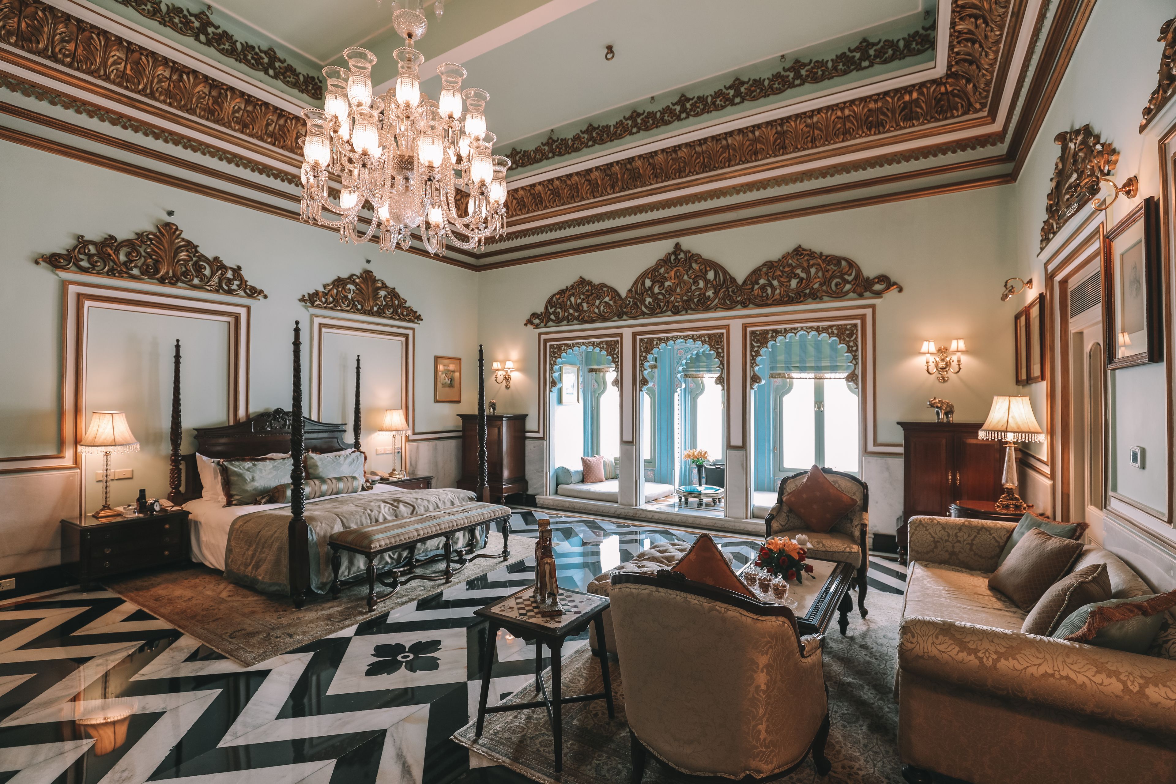 Un dormitorio lujoso con cama con dosel, techo ornamentado y candelabro.