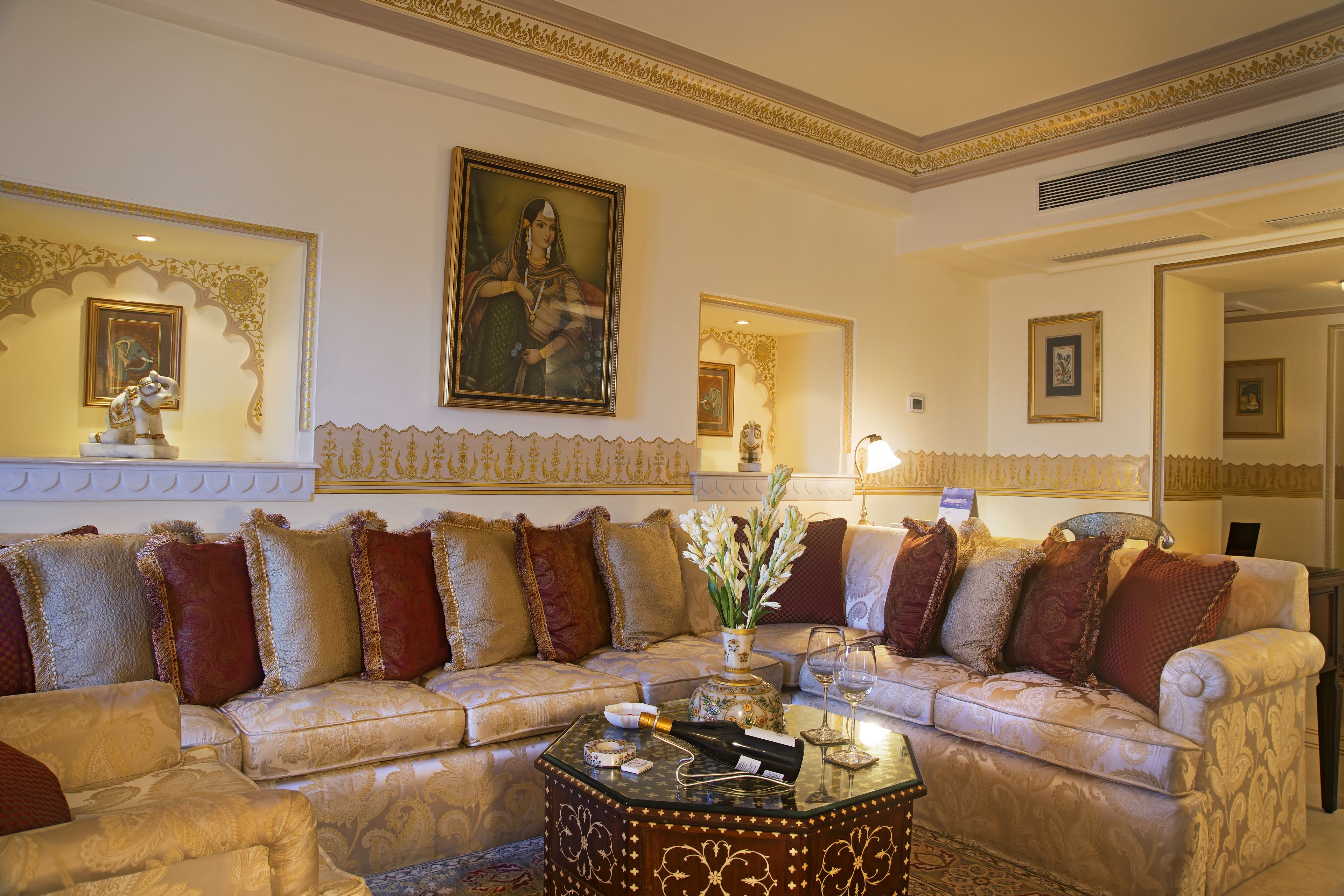 Un salon luxueux, doté d’un grand canapé, d’une table basse agrémentée d’objets décoratifs et de décorations murales raffinées.