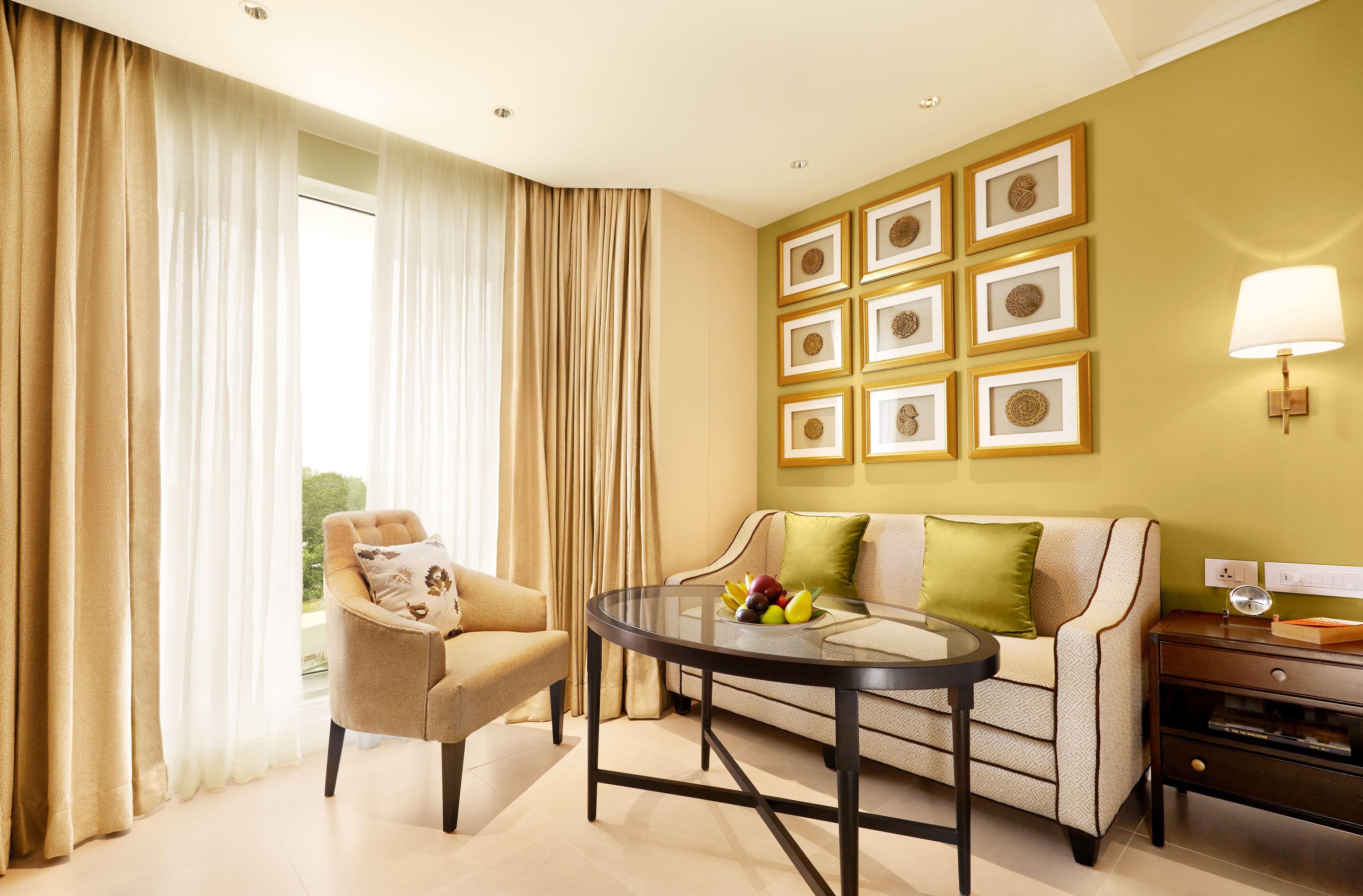 A modern living room with a sofa, armchair, and a round table with fruit.