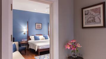 A bedroom with a bed, bedside table, lamp, and a vase with flowers.