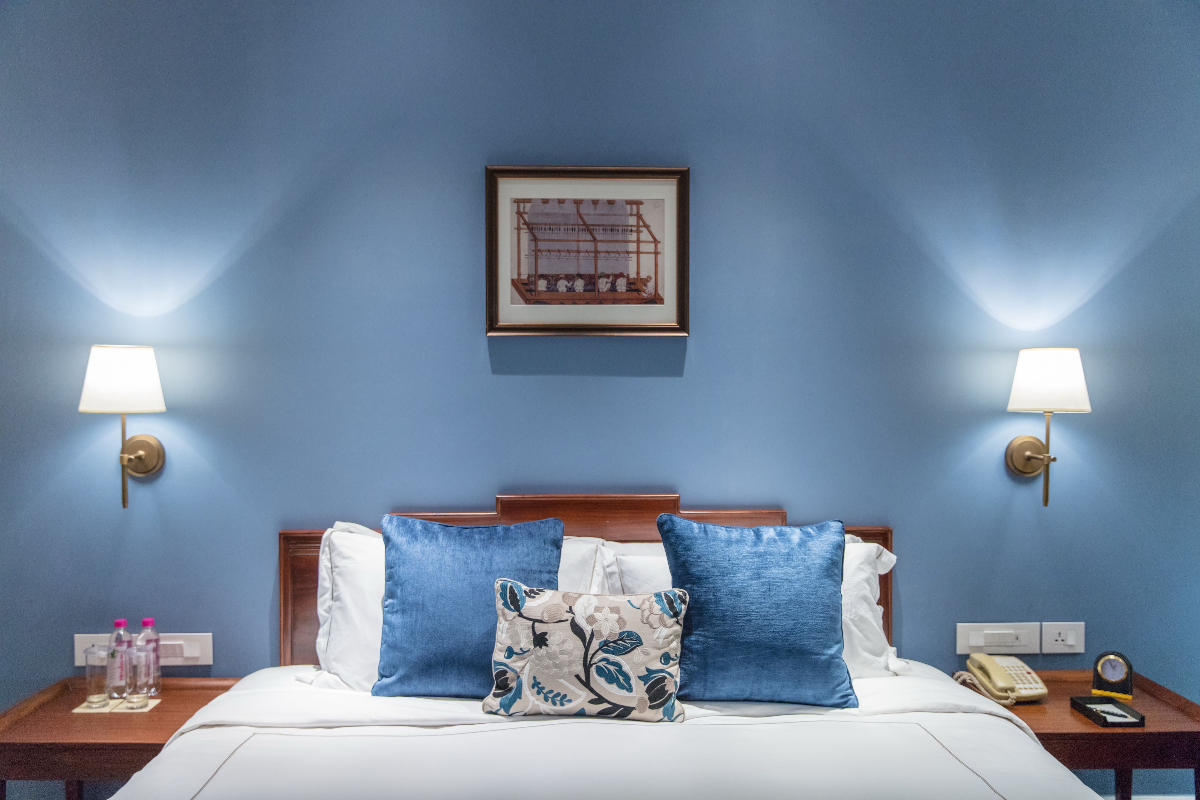 A hotel room with a bed, two nightstands, a framed picture on the wall, and a lamp on each nightstand.