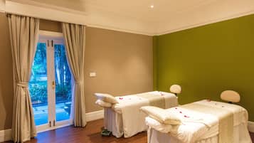 Relax in a serene space with two massage therapy beds, a green wall, and a glass door leading to an outdoor area.