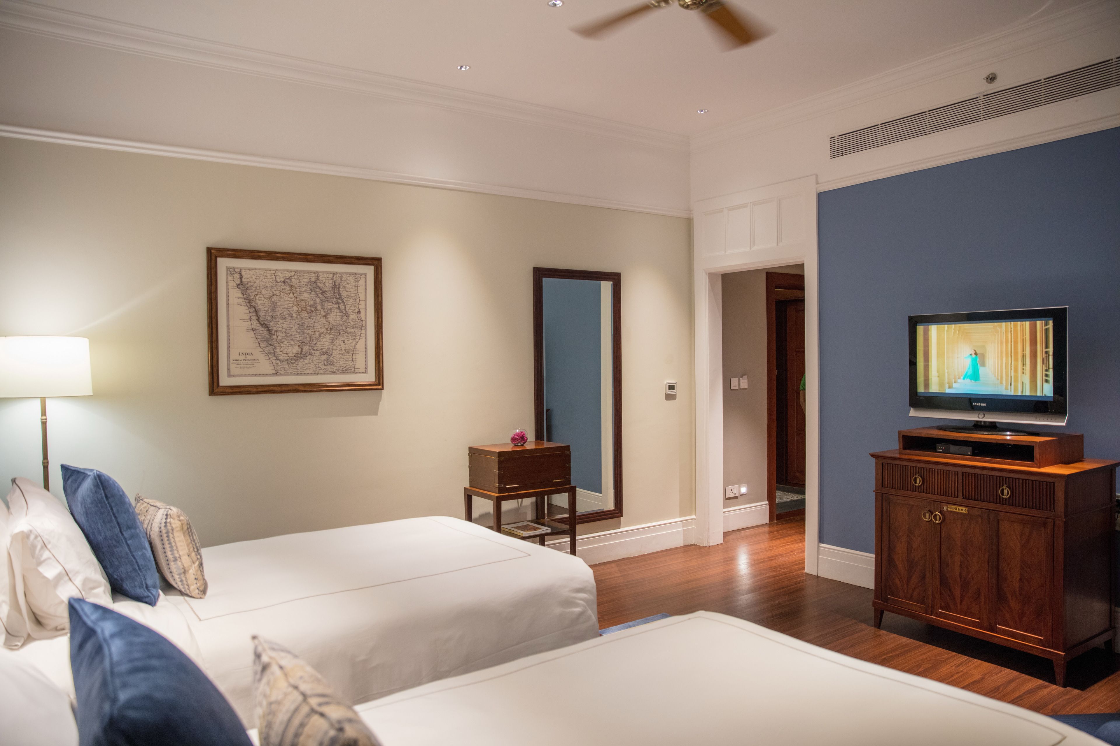 Habitación de hotel con dos camas, un televisor, un armario de madera y un mapa enmarcado en la pared.
