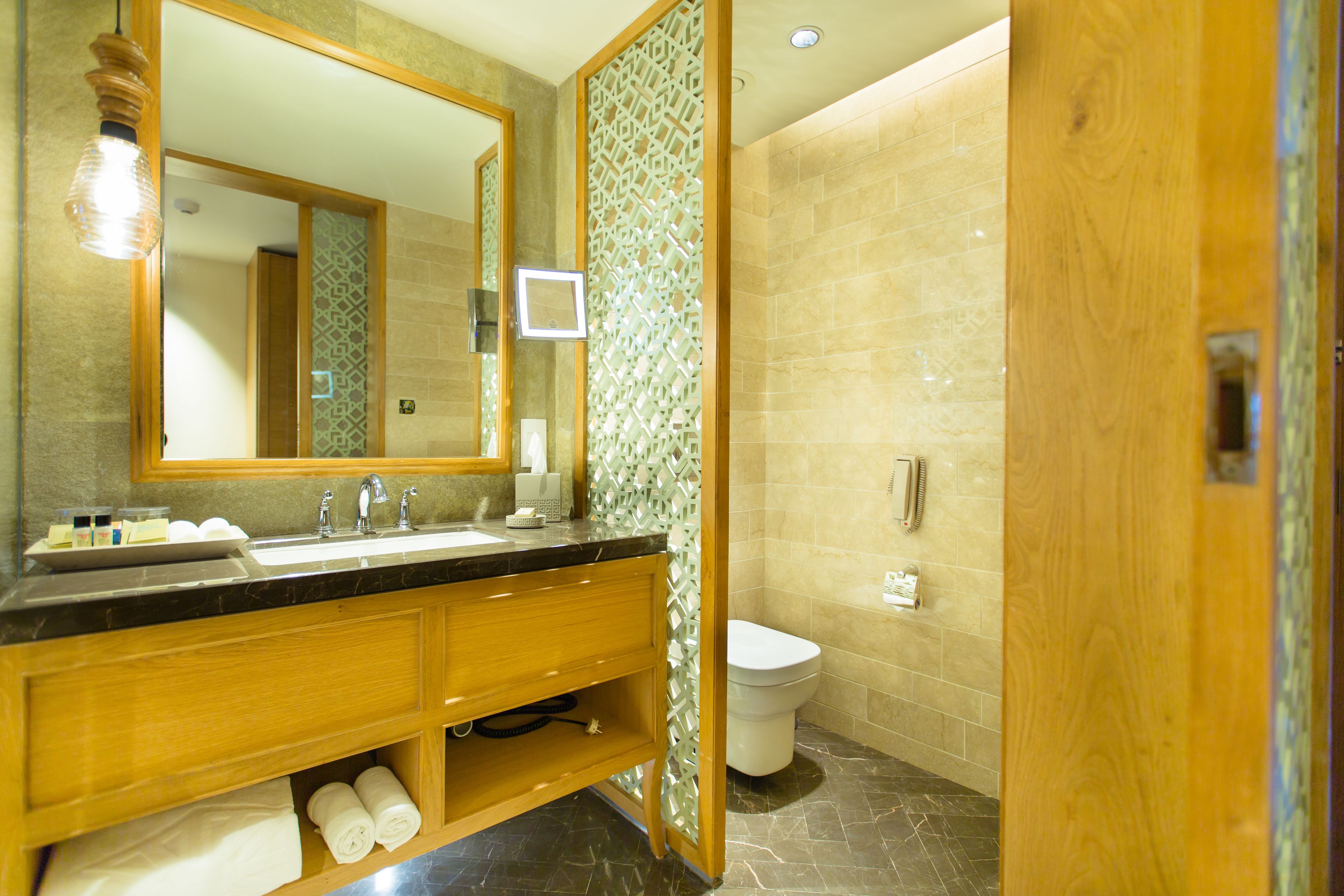 A modern bathroom with a large mirror, dual sinks, a toilet, and a shower area.