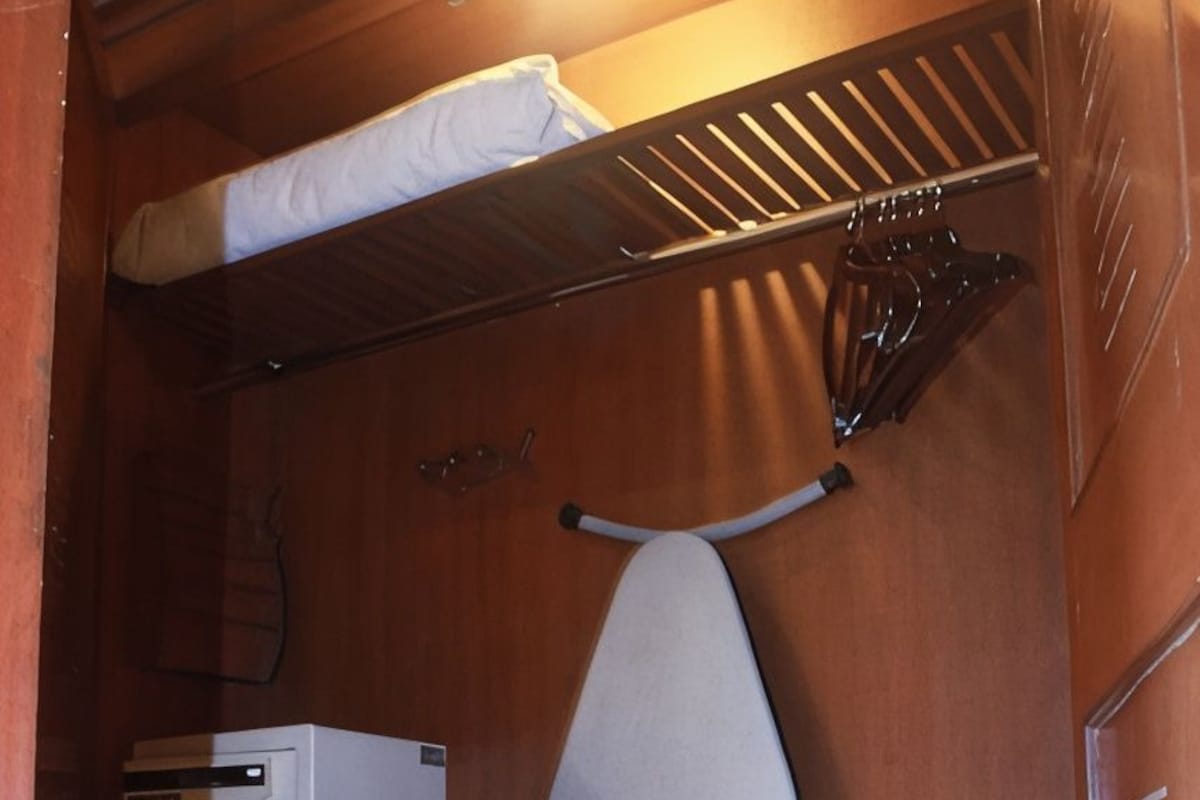 Un placard compact comprenant une tringle à vêtements, une boîte de rangement et une planche à repasser.