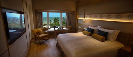 A hotel room with a large bed, a seating area with a table, and a view of the ocean.