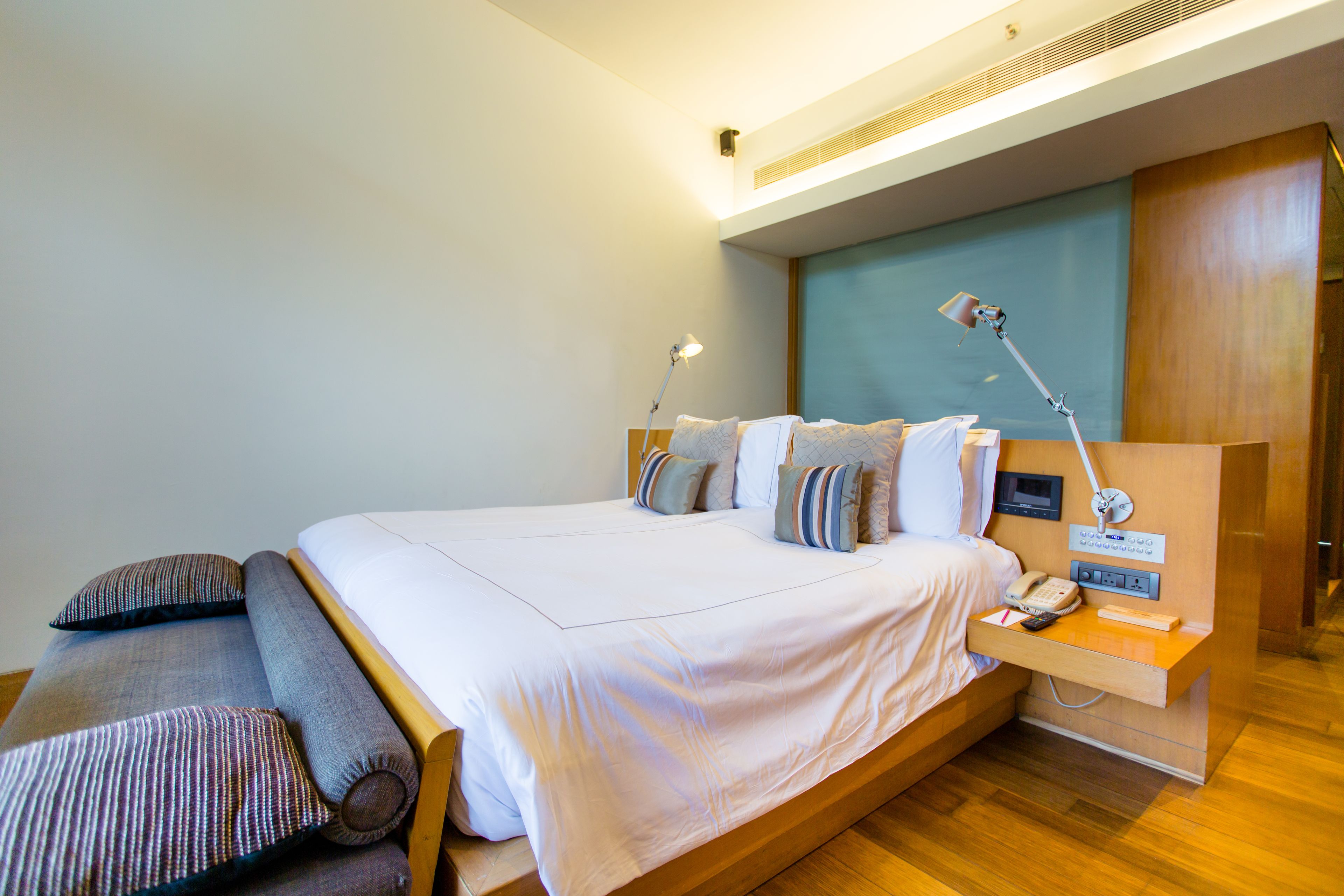 A modern hotel room with a large bed, bedside tables, a desk, and a desk lamp.