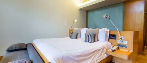 A modern hotel room with a large bed, bedside tables, a desk, and a desk lamp.