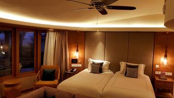 A hotel room with two beds, a ceiling fan, a desk with a telephone, and a view of the outdoors.