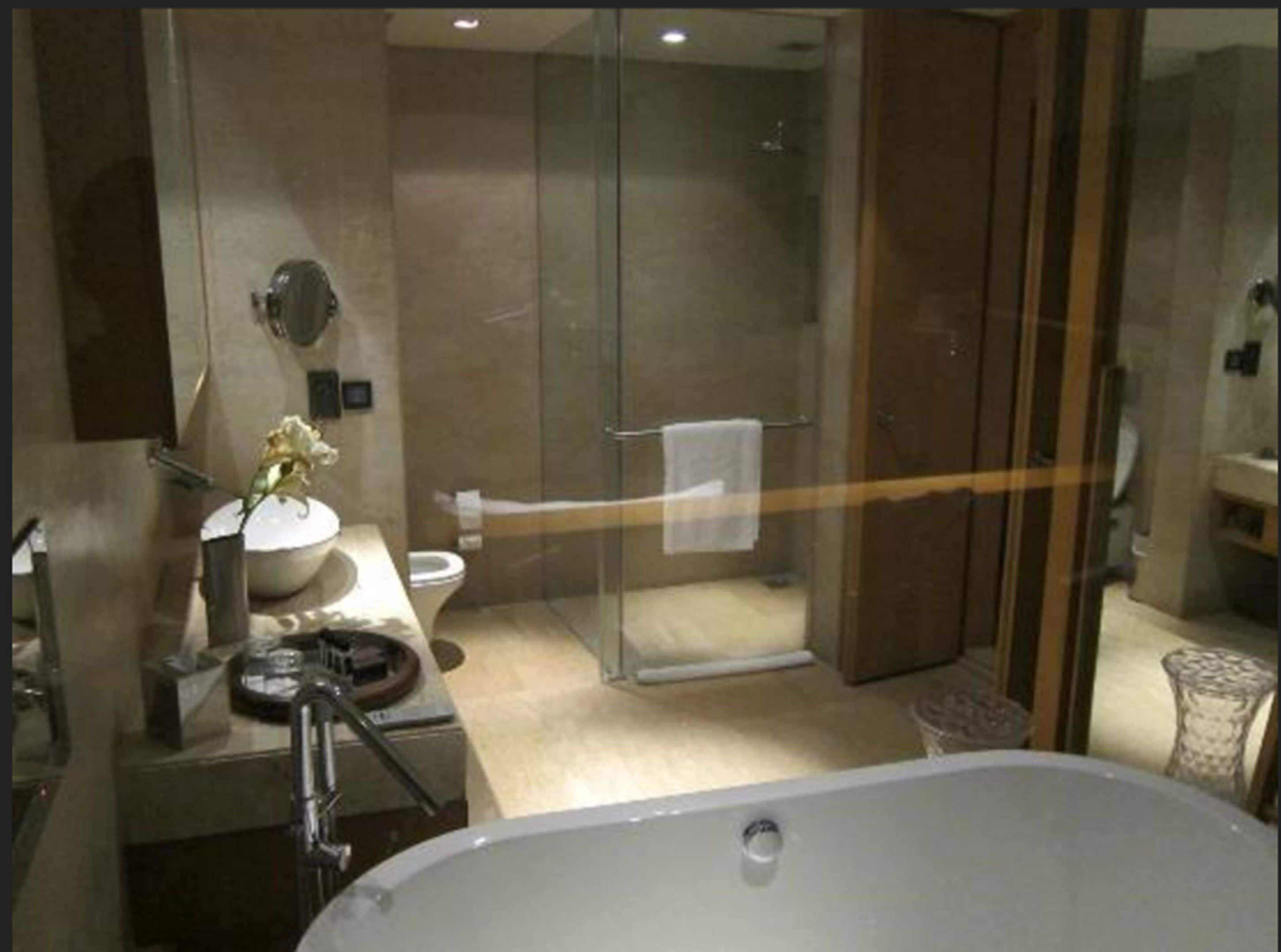 Une salle de bain moderne dotée d’une douche à parois de verre, d’une grande baignoire et d’un meuble-lavabo avec un évier et un miroir.