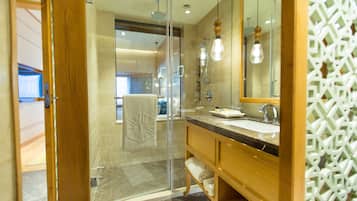 Un baño moderno con cabina de ducha de vidrio, tocador de madera con lavamanos y un espejo grande.