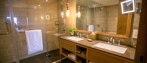 Un baño moderno con cabina de ducha de vidrio, lavamanos dobles y un espejo grande.