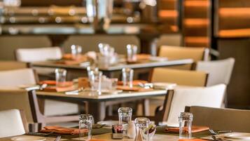 A restaurant with tables set for dining, featuring a central floral arrangement.