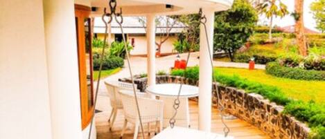 A covered outdoor area with a swing set, a table, and chairs.