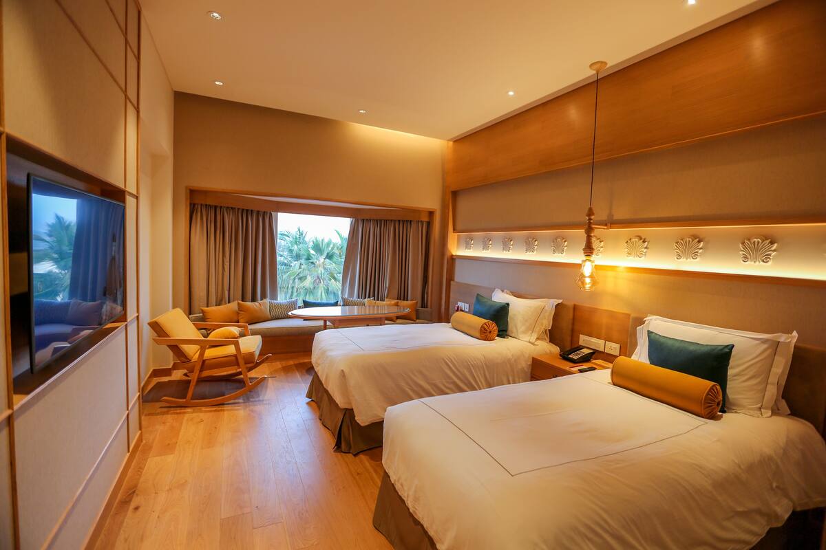 Habitación de hotel con dos camas, un sofá, un televisor y una ventana con cortinas.