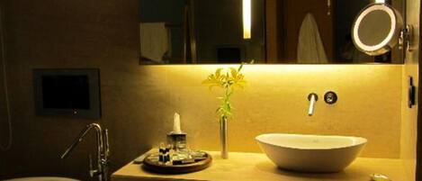 A modern bathroom with a freestanding bathtub, a large vessel sink, and a mirror with a round frame.