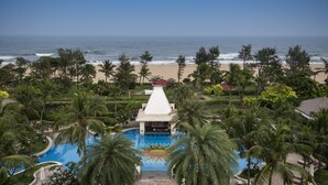 Een resort met een zwembad, omringd door palmbomen, een strand en uitzicht op de oceaan.