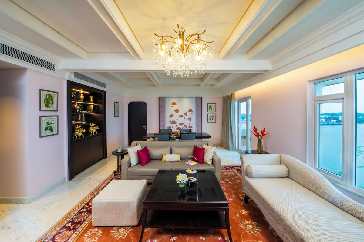 A spacious living room with a chandelier, a sofa, a coffee table, and a view of the water.