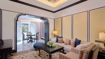 Habitación de hotel con sofá, sillón, mesa de comedor y candelabro.