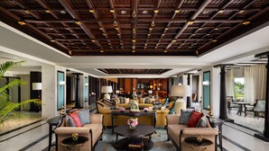 Un lobby espacioso con techo alto, asientos cómodos, una mesa de centro y una zona bien iluminada con estanterías y chimenea.