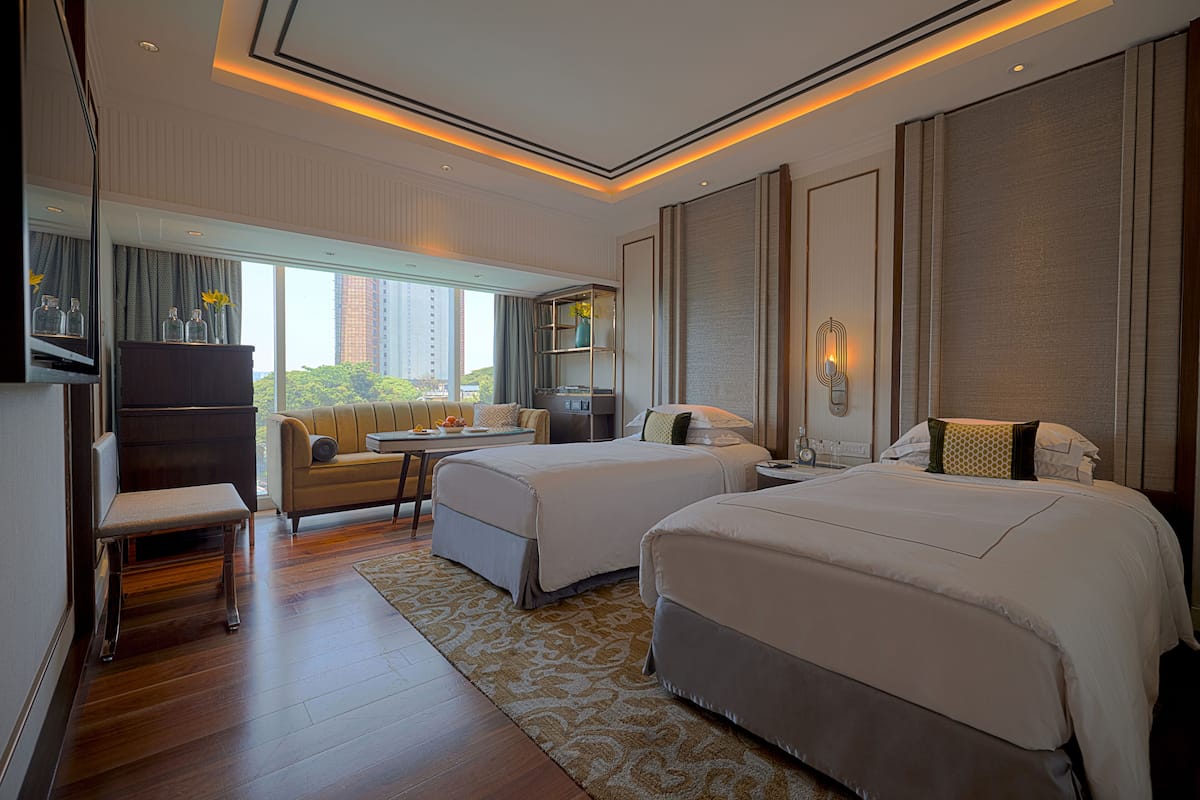 Une chambre d’hôtel avec deux lits, un canapé, une petite table et un téléviseur.