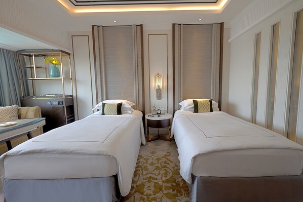 A hotel room with two beds, a small table, a desk, and a mirror.