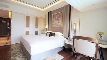 Ein modernes Hotelzimmer mit einem großen Bett, einem Schreibtisch mit Stuhl, einem Nachttisch und einem Bild an der Wand.