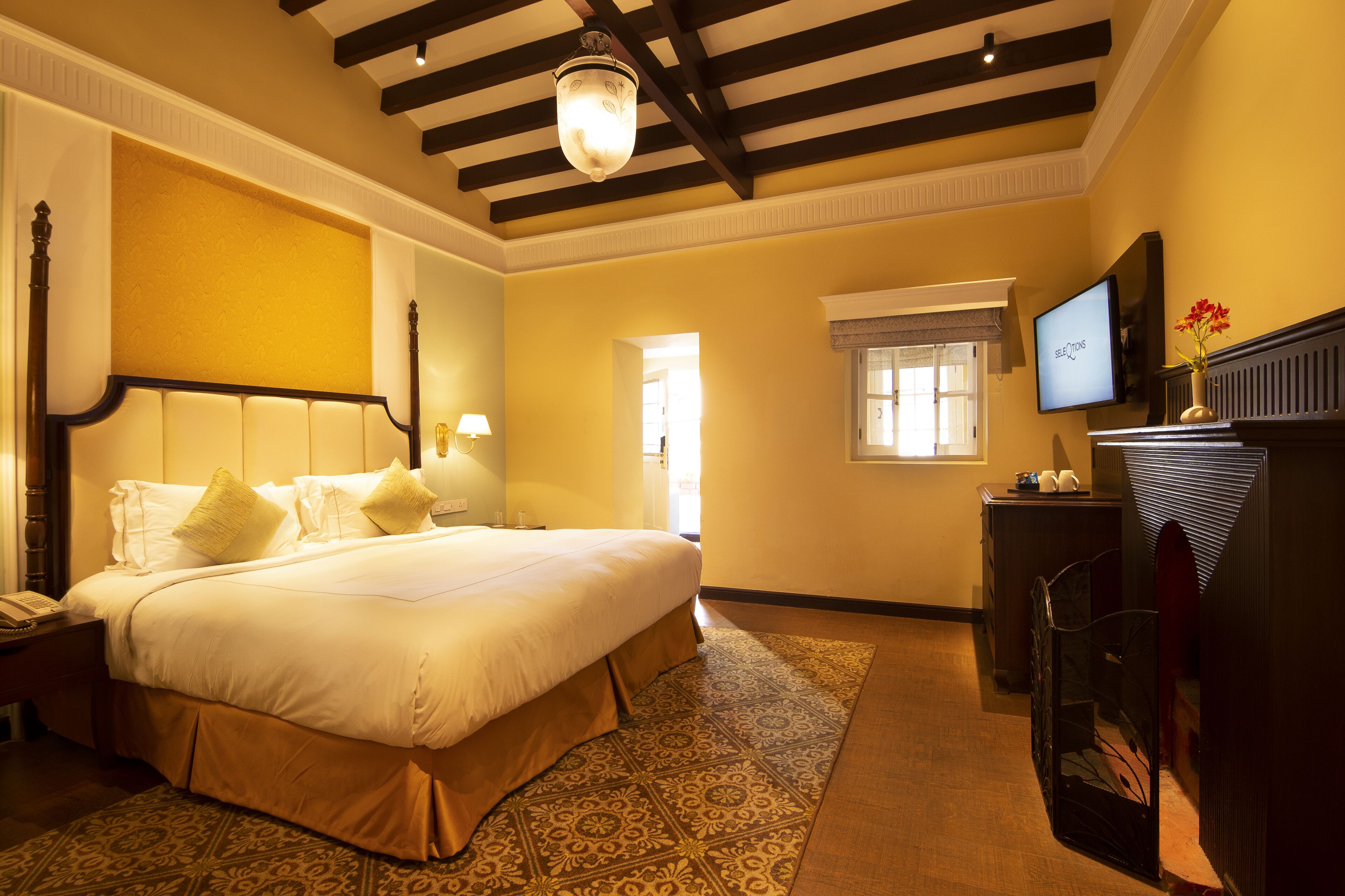 A hotel room with a large bed, a television, a desk, and a window.
