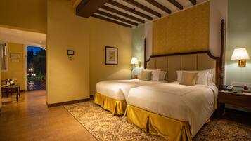 A hotel room with two beds, a wooden ceiling, patterned carpet, and a night view outside.
