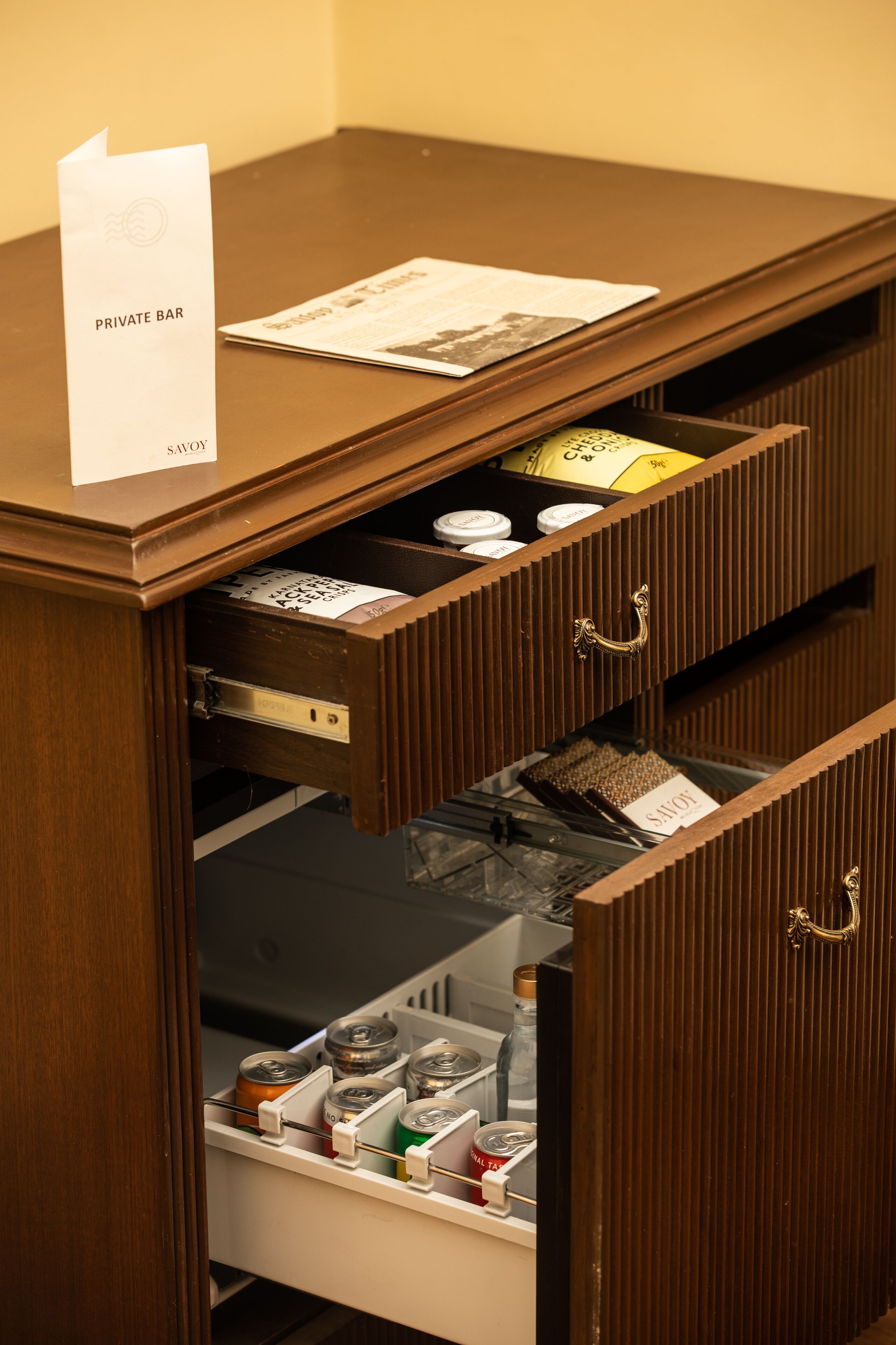 A wooden desk with a sign reading "PRIVATE BAR" and a menu. There are two drawers, one with a bottle and the other with a bottle opener.