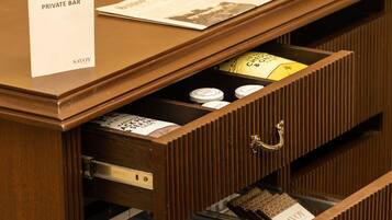 A wooden desk with a sign reading "PRIVATE BAR" and a menu. There are two drawers, one with a bottle and the other with a bottle opener.