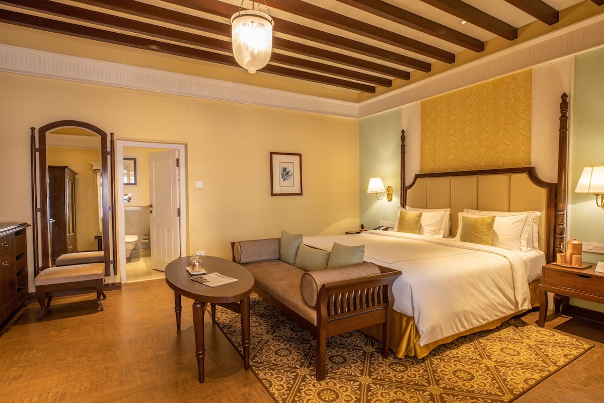 A hotel room with a bed, a sofa, a table, and a mirror.