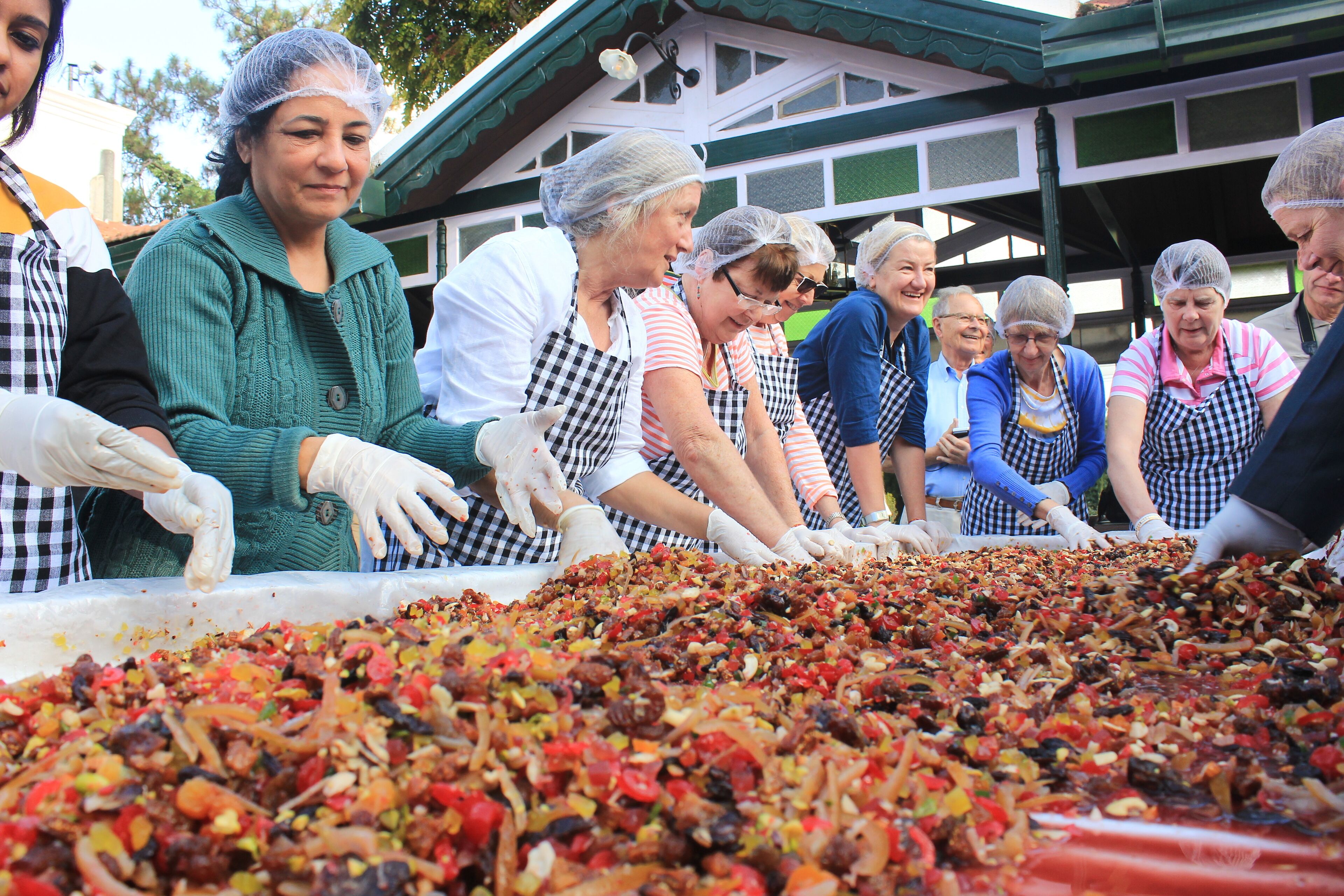 A group of people preparing a large dish with various ingredients.