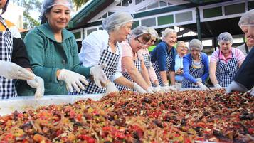 A group of people preparing a large dish with various ingredients.