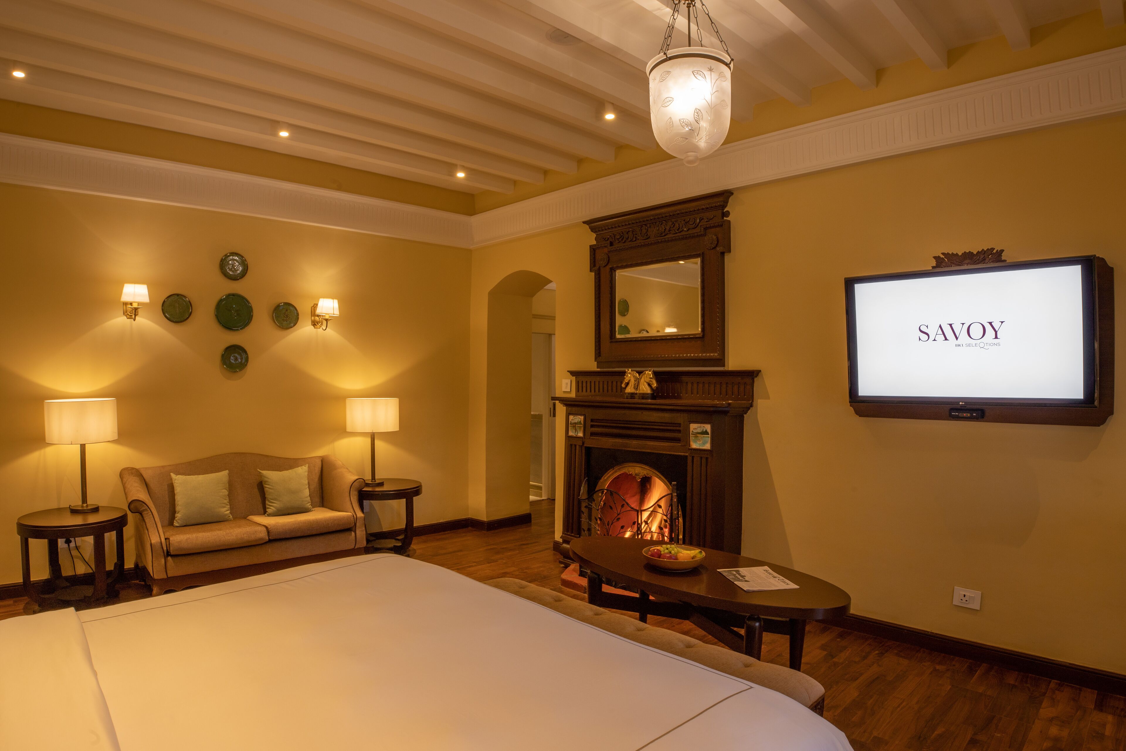 Una habitación de hotel con una cama grande, una chimenea, un televisor y un sofá.