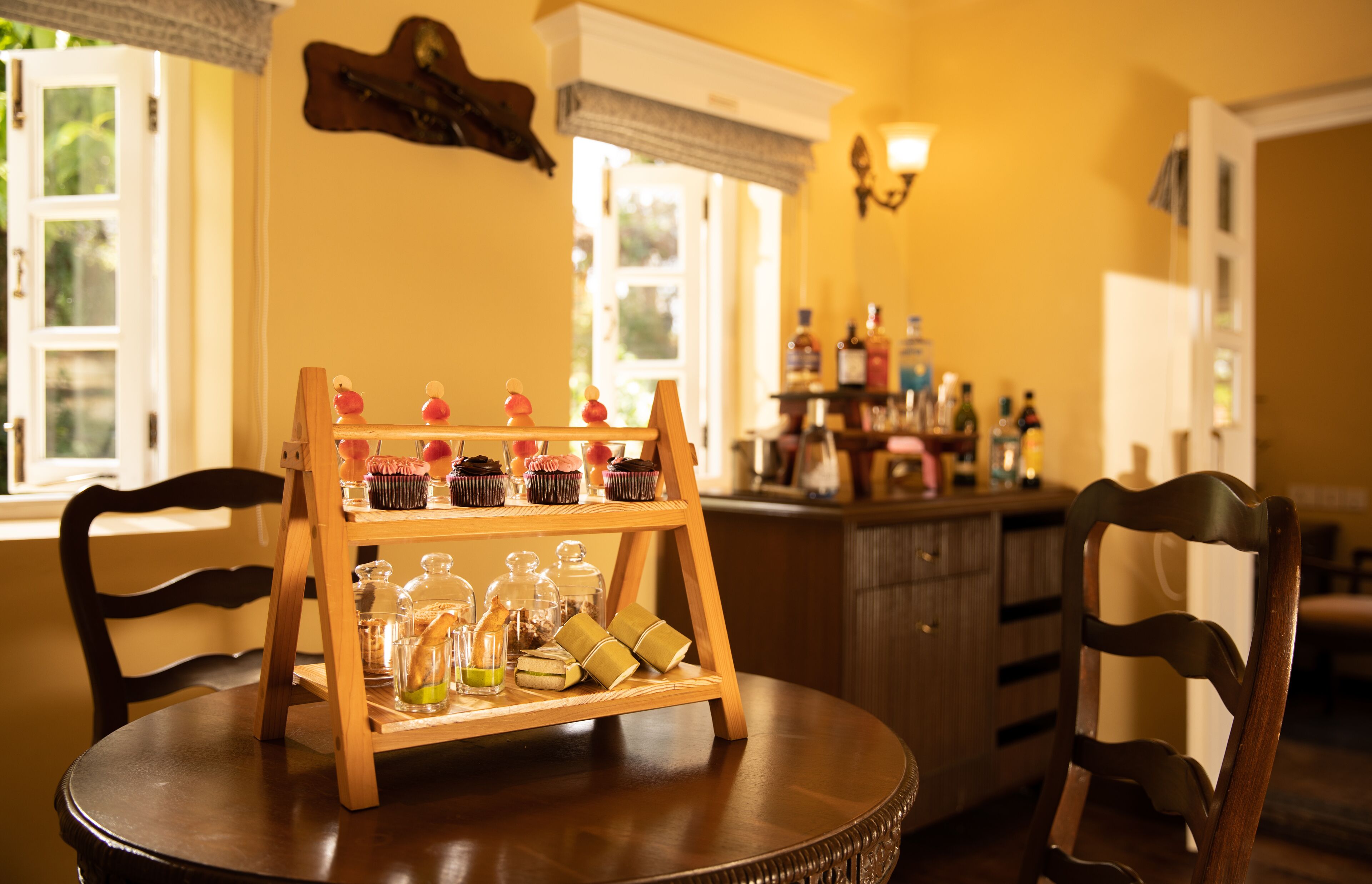 A wooden table with a tiered stand holding various food items and condiments.