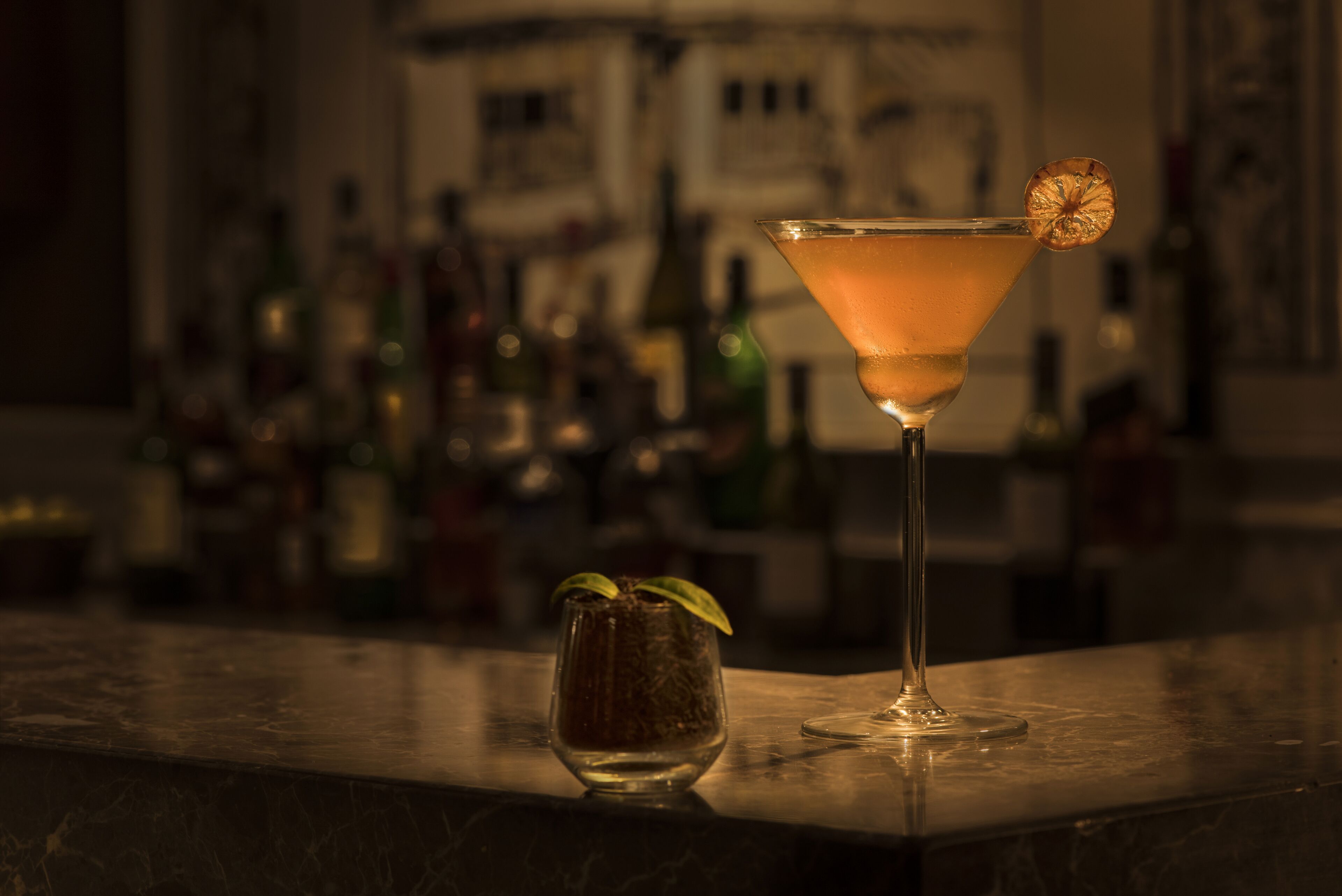 A bar setting with a martini glass and a small glass with a garnish.
