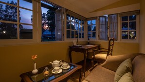 Una habitación acogedora con un sofá, una mesa con un juego de té y grandes ventanales que dan al exterior.