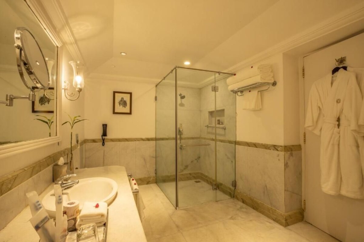 Un baño con ducha de vidrio, lavamanos y espejo.