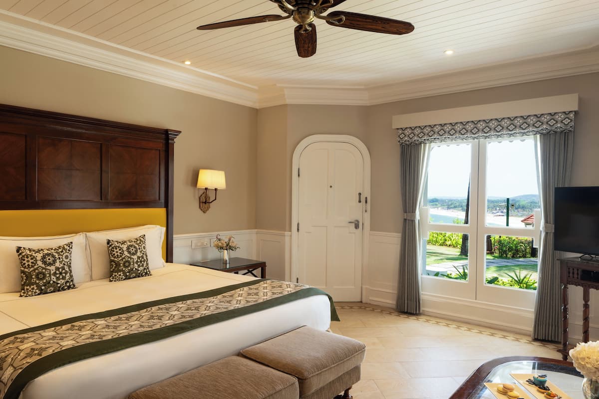 A hotel room with a large bed, a ceiling fan, a television, and a view of the outdoors.