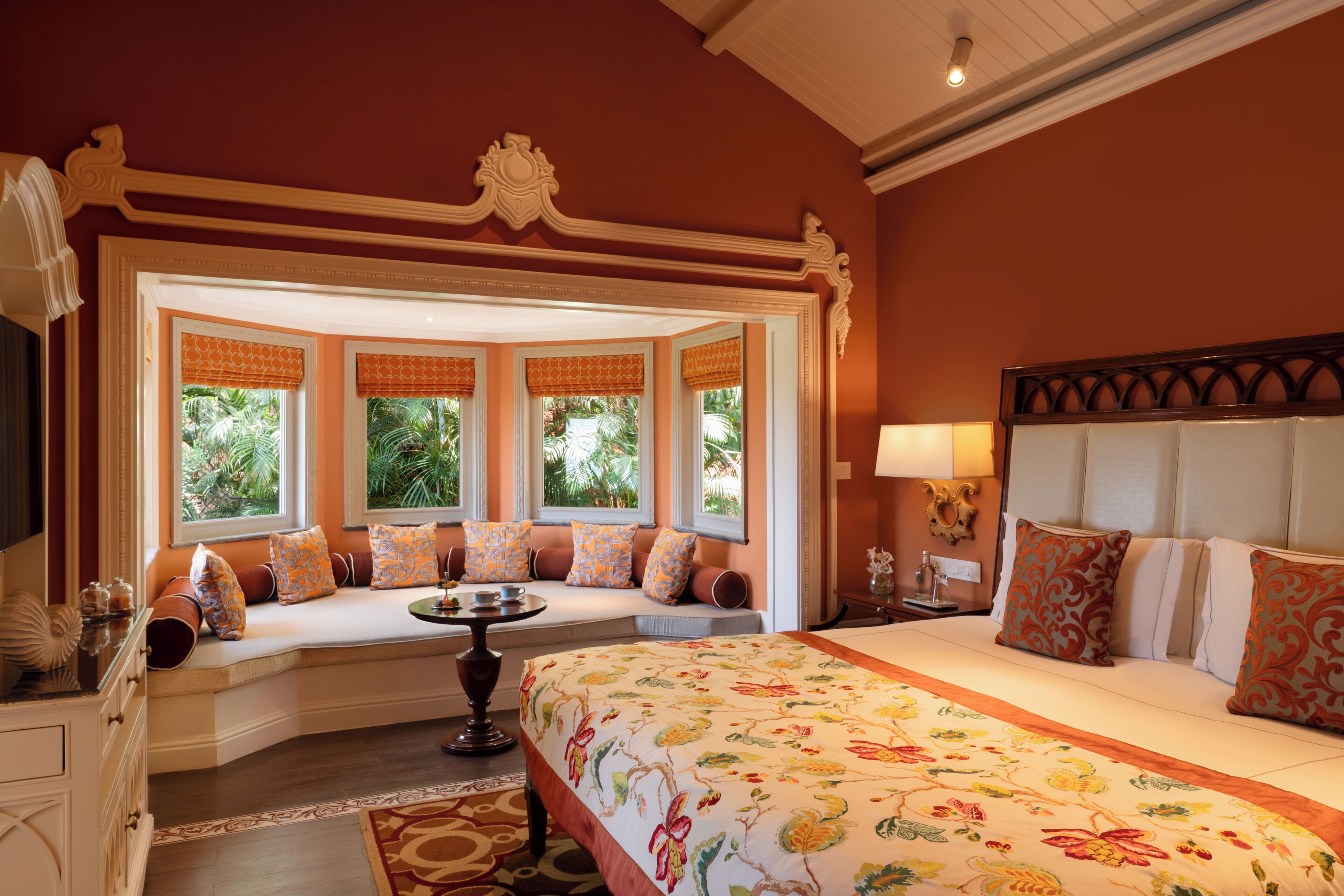 A room with a large bed, a seating area with a view, and a decorative ceiling.
