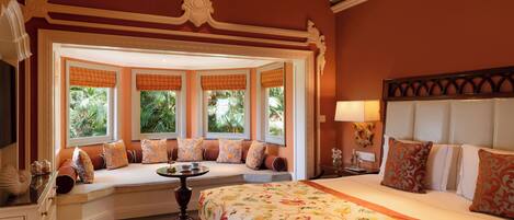 A room with a large bed, a seating area with a view, and a decorative ceiling.