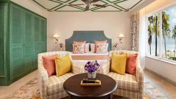 A hotel room with a bed, two sofas, a coffee table, and a view of palm trees through the window.