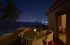 A balcony with a glass table, two wicker chairs, a candle, and two wine glasses. - Taj Fort Aguada Resort & Spa, Goa (Candolim)