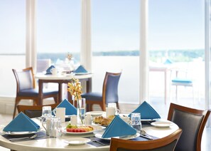 A dining table set with blue napkins, plates, and a glass of water. - Taj Fort Aguada Resort & Spa, Goa (Candolim)